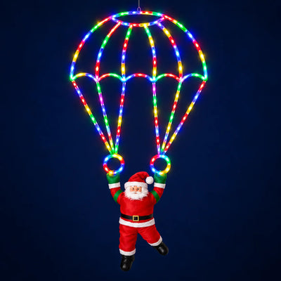 Papai Noel de paraquedas Folgaria com luz de LED colorida acesa, em fundo escuro