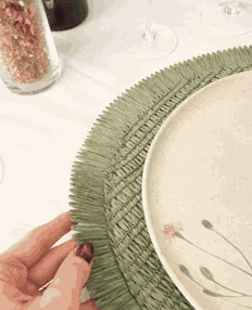 O jogo americano Comporta sendo colocado na mesa, com prato, taça e talher por cima